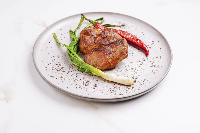 Framed Print : Succulent grilled meat sits on a textured plate surrounded by fresh scallions and bright red chili peppers
