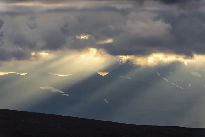 Framed Print : Sun rays fall through clouds in mountain landscape