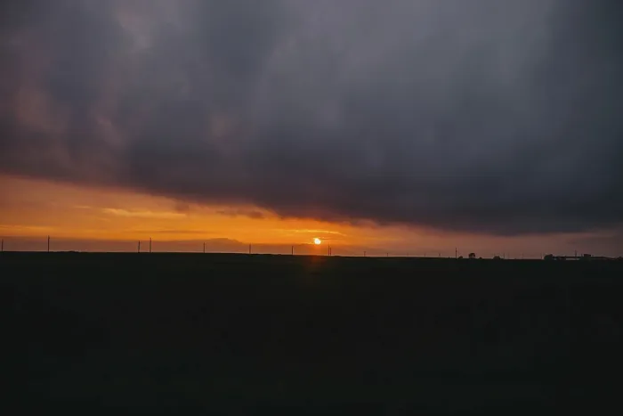 Framed Print : The sun sets behind clouds creating a dramatic