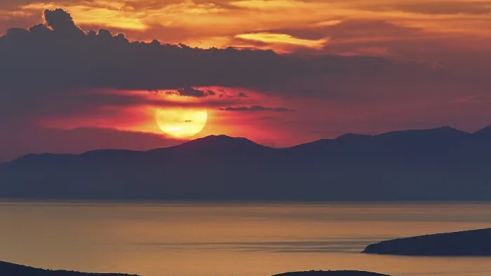 Framed Print : Sunset, sun large under grey clouds and directly above a mountain range Framed Print : Sunset, sun large under grey clouds and directly above a mountain range