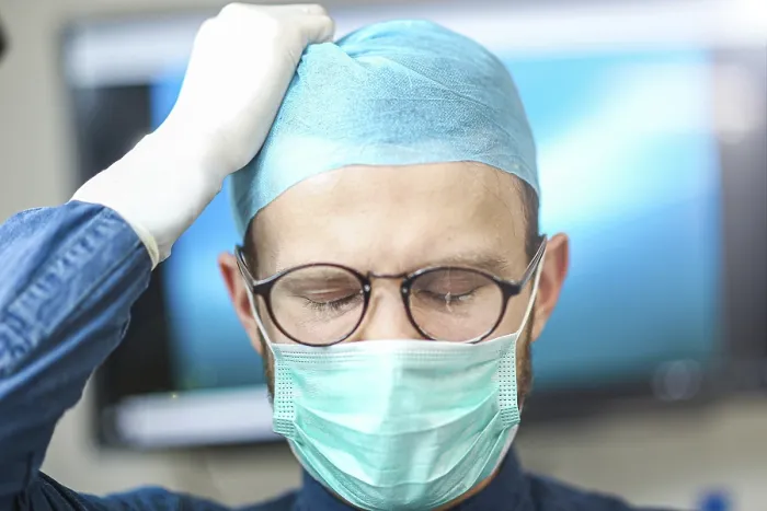 Framed Print : A surgeon adjusting his cap, appearing concentrated and careful Framed Print : A surgeon adjusting his cap, appearing concentrated and careful