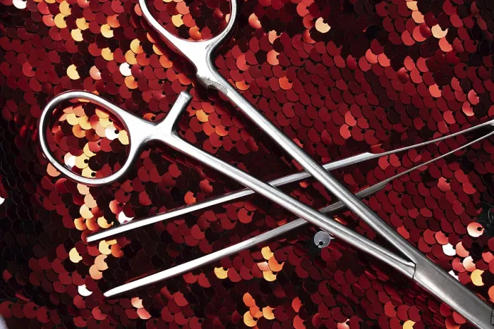 Framed Print : Surgical tools on a red sequin background