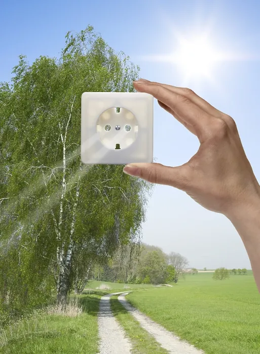 Framed Print : Symbolic solar energy theme showing a idyllic outdoor scenery with human hand holding a electrical socket in front of Framed Print : Symbolic solar energy theme showing a idyllic outdoor scenery with human hand holding a electrical socket in front of