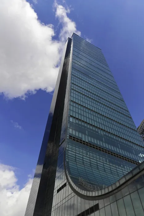 Framed Print : A tall modern office building with a glass facade under a blue sky