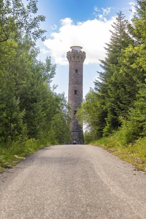 Framed Print : A tall stone tower rises into the sky above a forest path