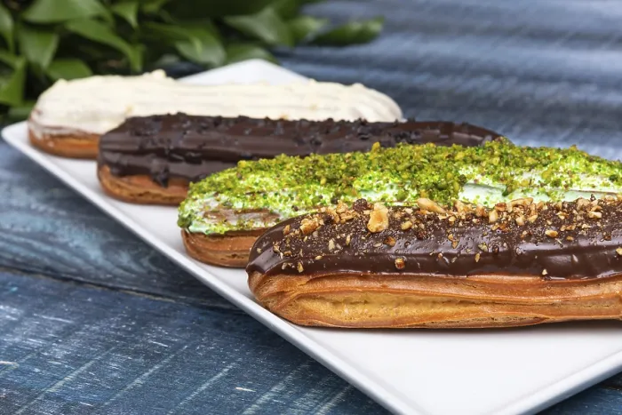 Framed Print : Tasty chocolate eclair cakes with leaves on the blue background