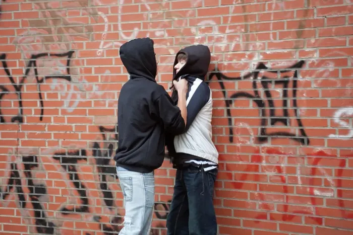 Framed Print : Teenager pushing a smaller boy violently against a wall, posed scene
