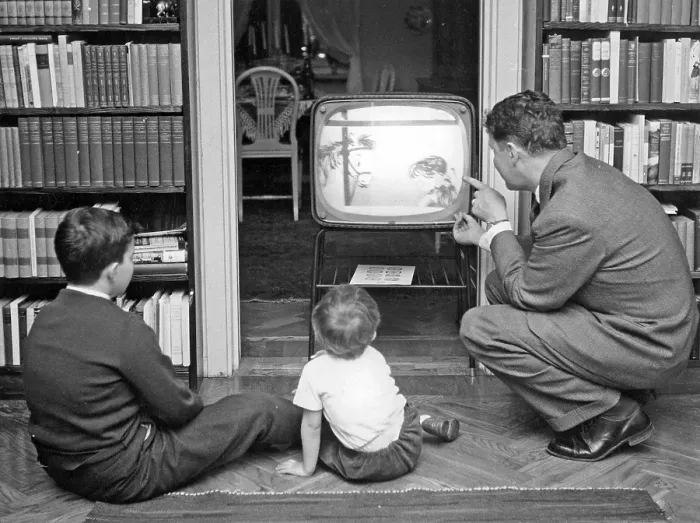 Framed Print : Television in the 1950s. A father with his children in front of the television set looking at a children's program