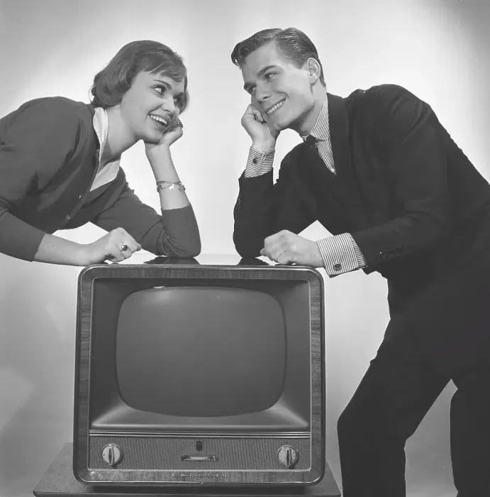Framed Print : Television in the 1950s. A young couple is pictured beside a typical 50s television set Framed Print : Television in the 1950s. A young couple is pictured beside a typical 50s television set