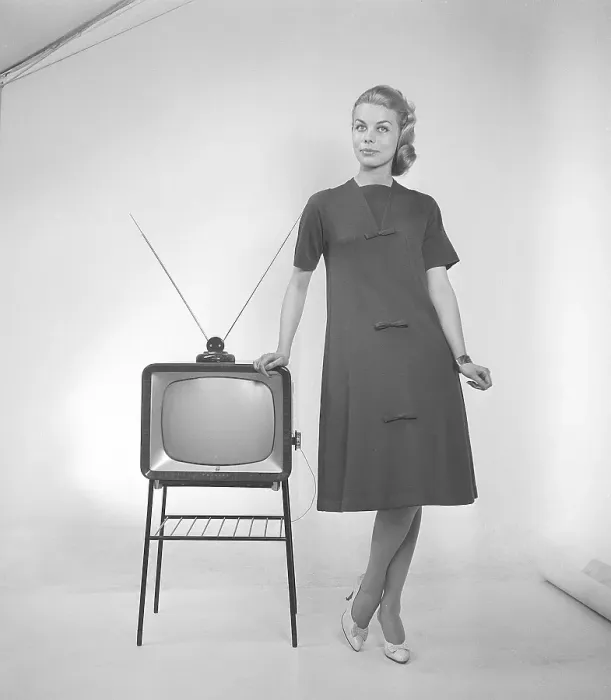Framed Print : Television in the 1950s. A young woman is standing dressed in a typical 50s dress beside a televison set with an table antenna on top of it. In 1952 1.4 million households in Britain had a television. Photo Kristoffersson ref BZ26. Sweden 1952