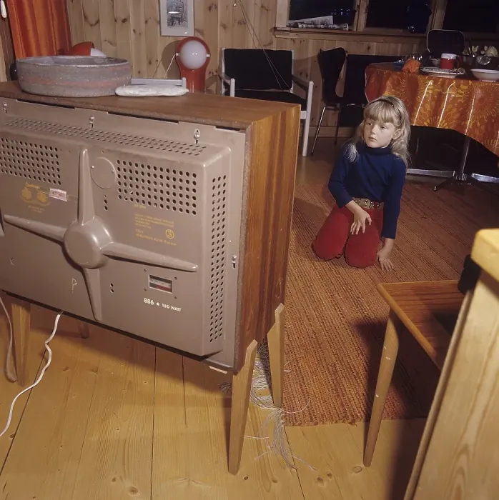 Framed Print : Television in the 1960s. A girl is sitting in front of a television set with her eyes on the screen and the program