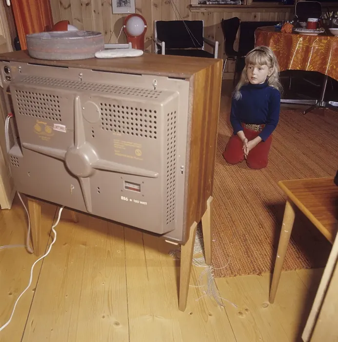 Framed Print : Television in the 1960s. A girl is sitting in front of a television set with her eyes on the screen and the program
