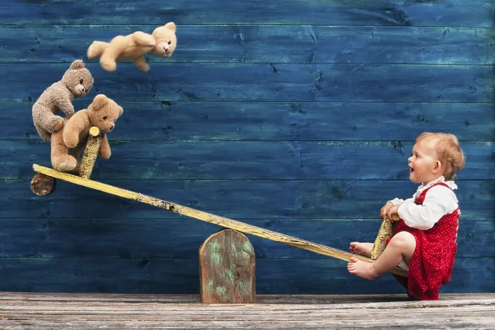 Framed Print : Three-year-old girl with teddy bear on seesaw