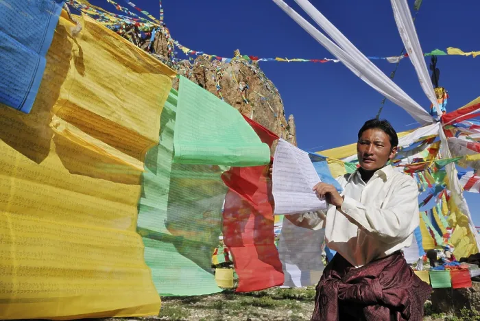 Framed Print : Tibetan pilgrim hanging prayer flags for the upcoming ceremony on Namtso Lake