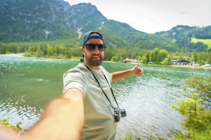 Framed Print : Tourist with vintage camera taking a selfie with thumbs up at lake dobbiaco in the italian dolomites during summer