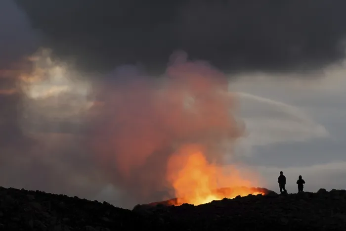 Framed Print : Tourists in front of reddish illuminated smoke cloud