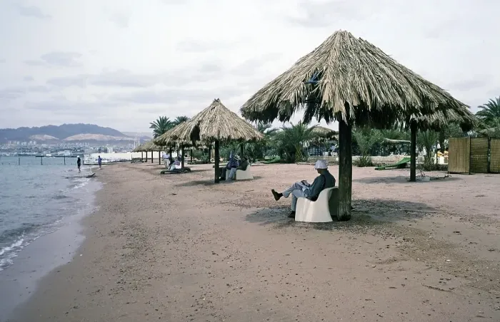 Framed Print : Tourists sitting in the shade on a sandy beach on the Red Sea coast, Aqaba. Jordan, 1998