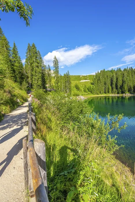 Framed Print : Tourists walking on gravel path along shore of lake carezza