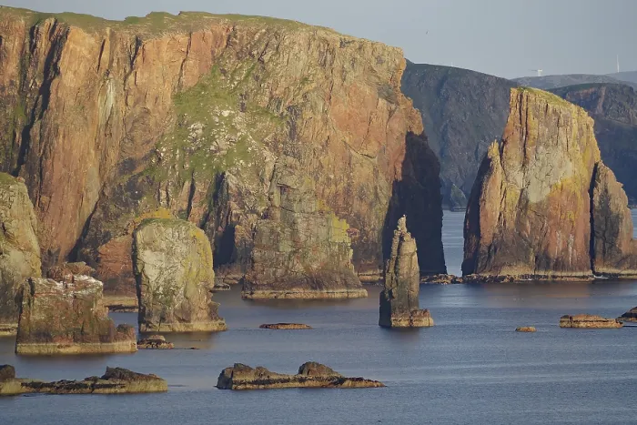 Framed Print : Towering cliffs and rocks in the sea under a clear sky