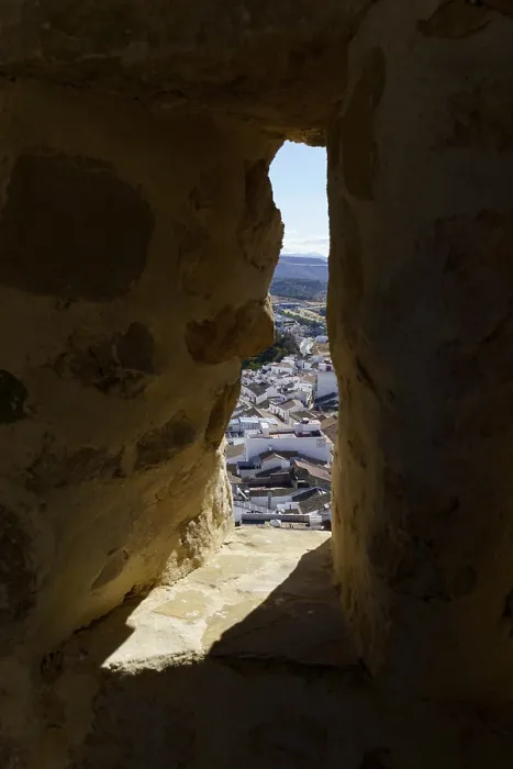 Framed Print : Town of olvera rooftops seen through a dark narrow window in a historic stone castle in olvera