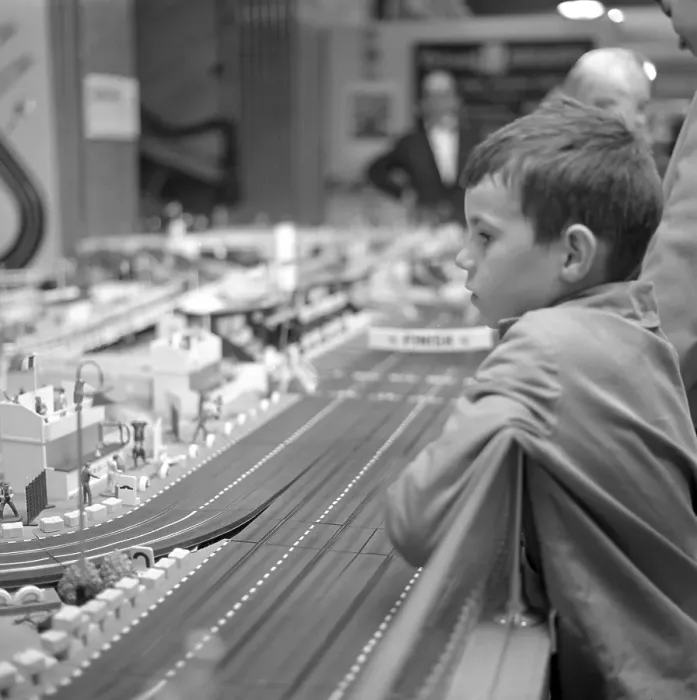 Framed Print : Toys in the 1960s. A boy fascinated by a miniature racing track by Scalextric