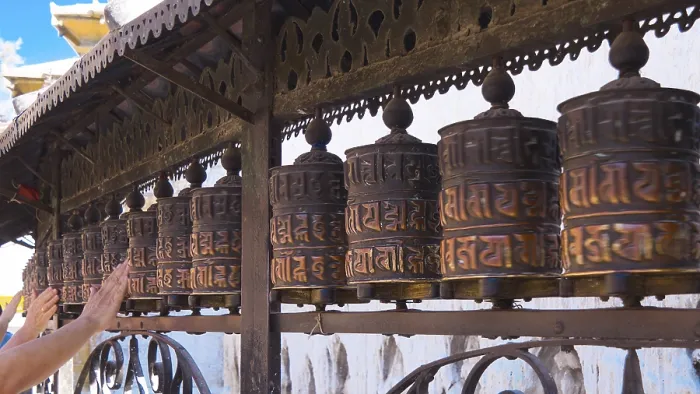 Framed Print : Traditional, artfully designed metal prayer wheels are placed in a row and are touched by hands