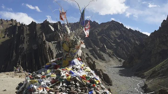 Framed Print : Traditional prayer flags on a stone hill in a wide mountain valley with a dry riverbed