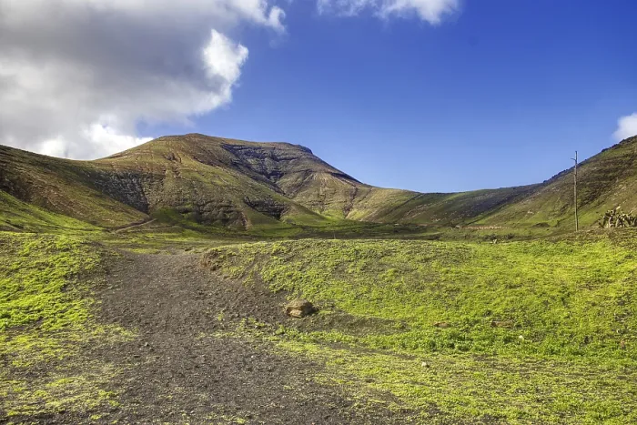 Framed Print : Trail leads through green hills under a sunny sky