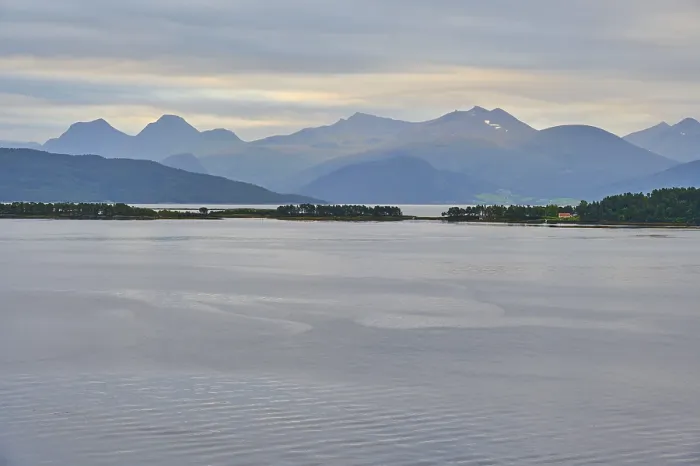 Framed Print : A tranquil fjord landscape with mountains in the background and islands covered by a cloudy sky Framed Print : A tranquil fjord landscape with mountains in the background and islands covered by a cloudy sky