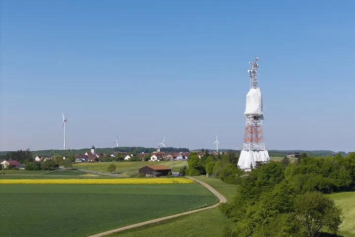 Framed Print : A transmission tower and wind turbines near a village under a blue sky