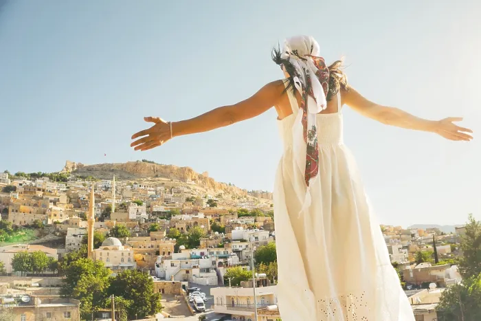 Framed Print : Traveler woman in white dress arms outstretched looking over panoramic view of historic city of Mardin Turkey with