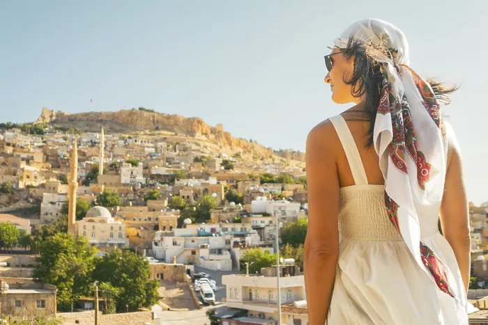 Framed Print : Traveler woman in white dress looking over panoramic view of historic city of Mardin Turkey with mosque minarets