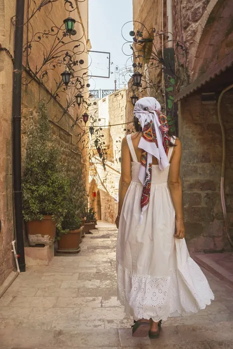 Framed Print : Traveler woman in white dress walking through narrow stone alley in historic city of Mardin Turkey with traditional Framed Print : Traveler woman in white dress walking through narrow stone alley in historic city of Mardin Turkey with traditional