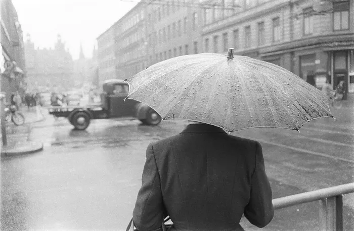 Framed Print : Umbrellas in the 1950s. The rain is pouring and a woman is seen holding an umbrella over herself Framed Print : Umbrellas in the 1950s. The rain is pouring and a woman is seen holding an umbrella over herself