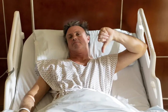 Framed Print : Unhappy patient in hospital bed giving thumbs down