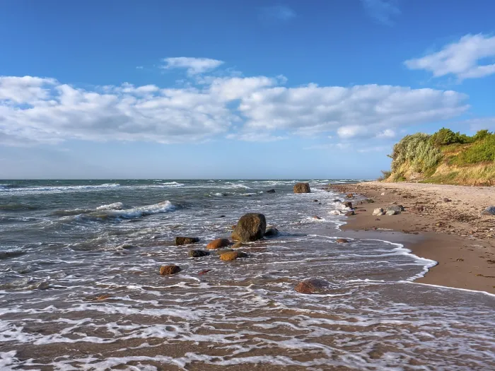 Framed Print : Unspoiled secluded stretch of coast with cliffs and boulders in the surf on the beach of the stormy Baltic Sea
