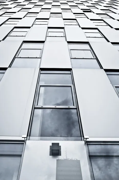 Framed Print : Upward view of a modern building with glass windows reflecting the cloudy sky