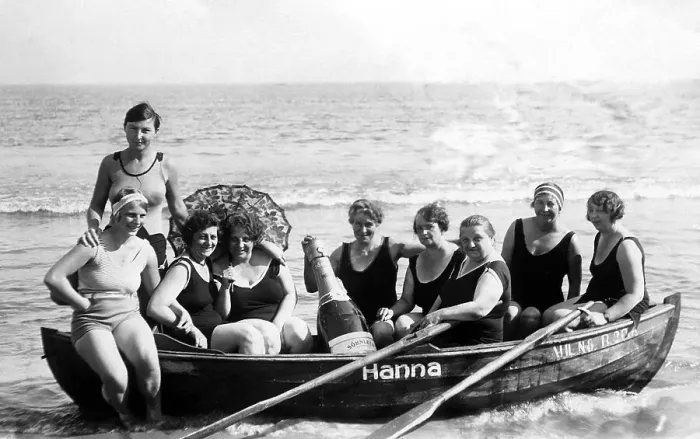 Framed Print : Vacation, nine women in swimsuit and with big champagne bottle on the beach in a rowing boat