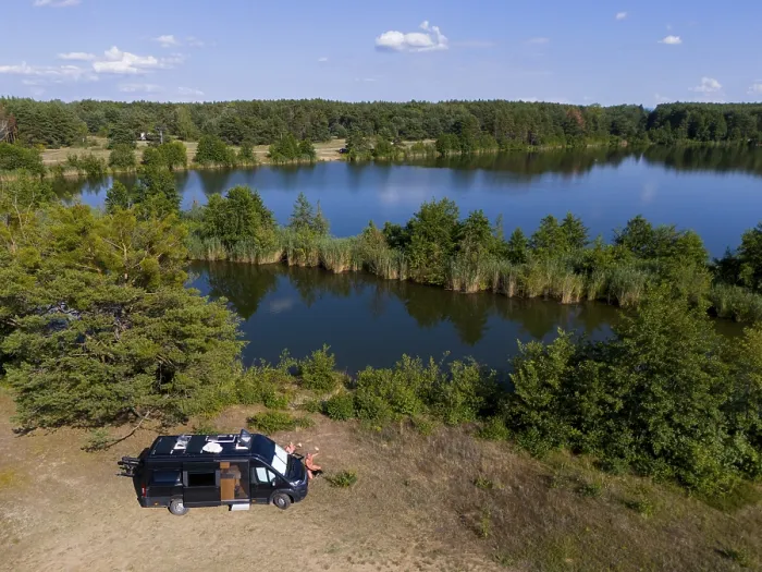 Framed Print : A van stands by a forest lake, surrounded by lush greenery and a blue sky Framed Print : A van stands by a forest lake, surrounded by lush greenery and a blue sky