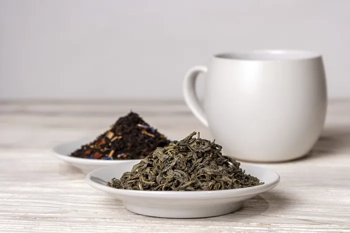 Framed Print : Varieties of black and green tea in saucers on a white background
