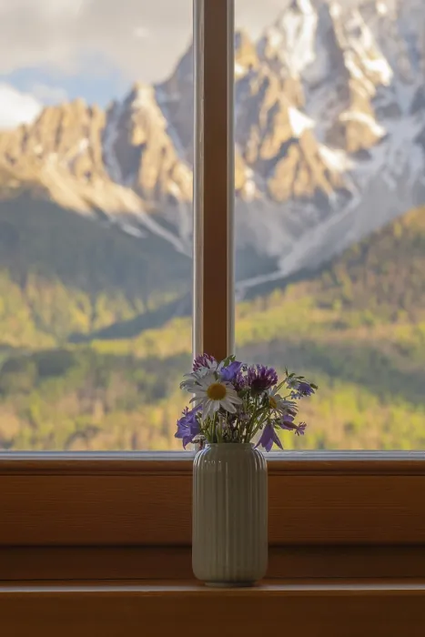 Framed Print : A vase with meadow flowers stands on the windowsill in the background the mountains of the Dolomites