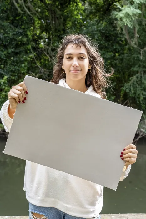 Framed Print : Vertical shot of a Woman holding a blank sign by the river