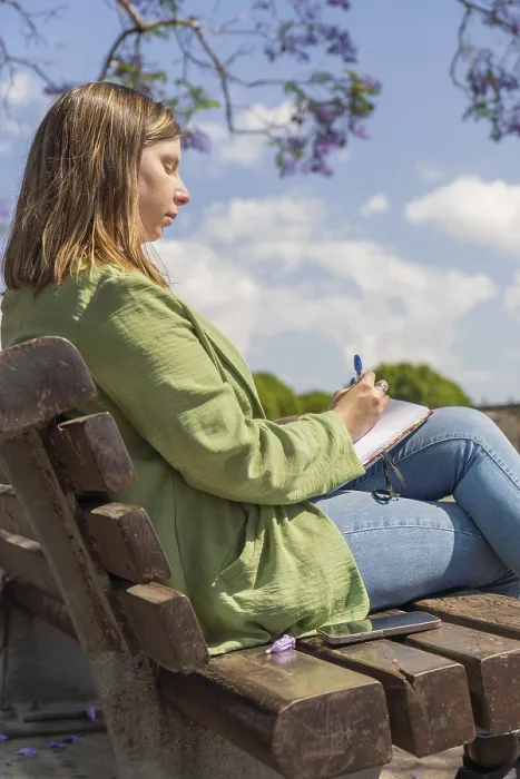 Framed Print : A vertical shot of a young woman sitting on a bench in a park Framed Print : A vertical shot of a young woman sitting on a bench in a park
