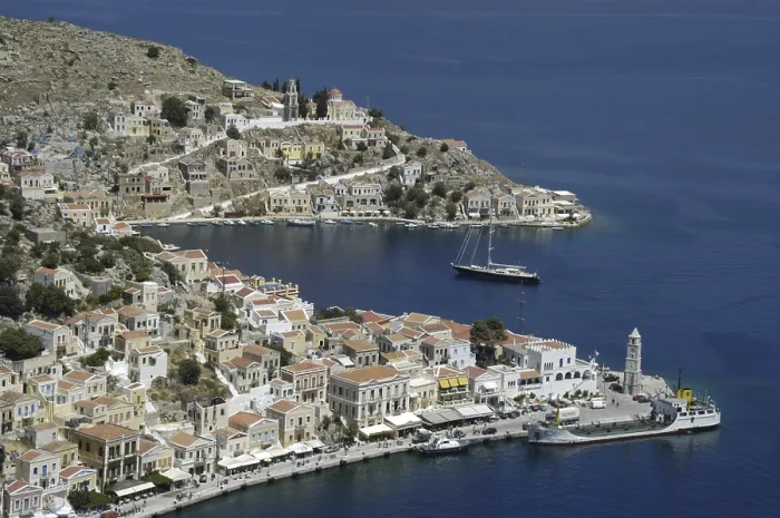 Framed Print : View of the city harbour and a sailboat Island of Symi Greece