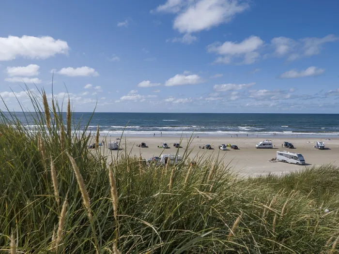Framed Print : View over dunes to a car beach on the North Sea with campervans by the sea under a blue sky