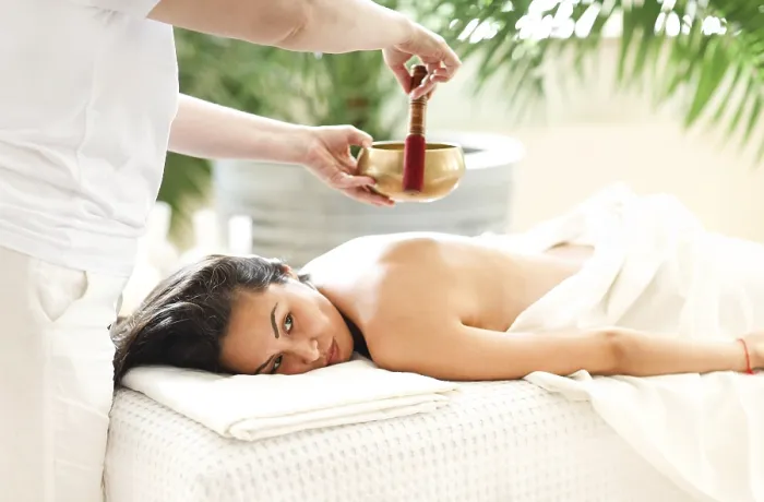 Framed Print : Side view of female therapist using singing bowl over back of relaxed Asian woman in spa salon