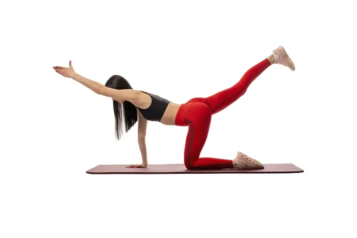 Framed Print : Side view of flexible female in sportswear standing on mat in pose and practicing yoga on white background