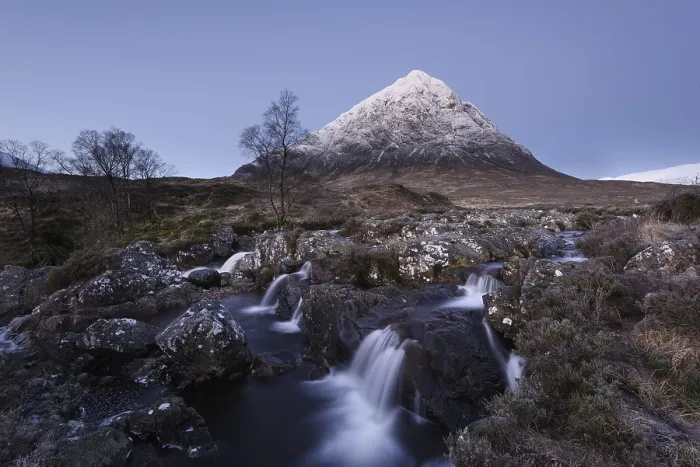Framed Print : View of moorland with small waterfalls in rocky stream and snow-capped mountain in background at dawn