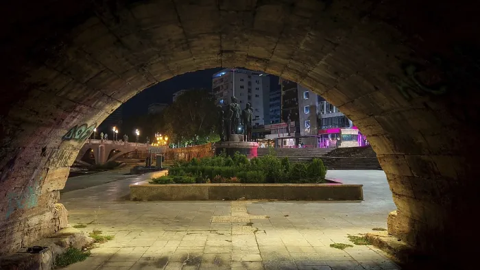 Framed Print : View through a stone archway of an illuminated square with monuments at night