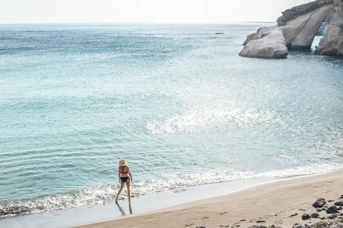 Framed Print : Back view of unrecognizable woman strolling along the shore of Gerontas Beach on the island of Milos in Greece